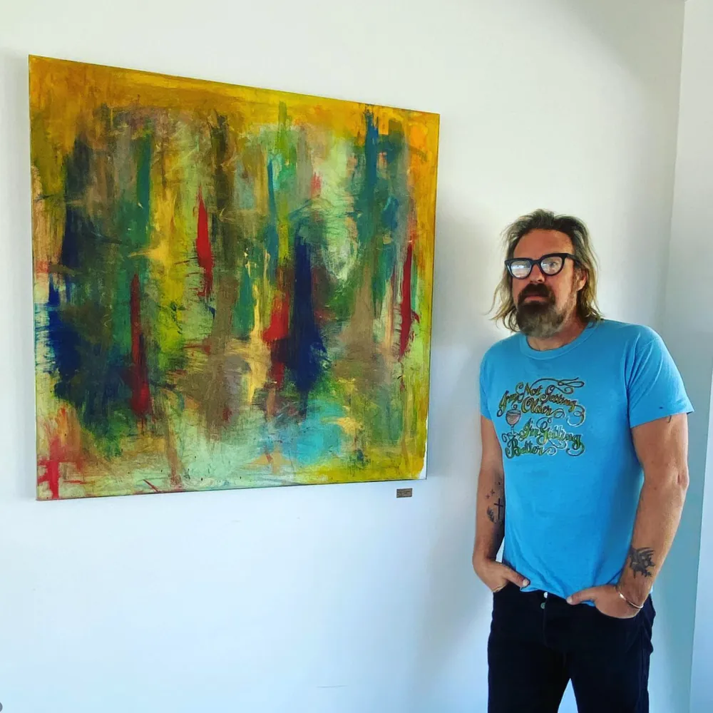 Brad Byrd standing next to one of his abstract paintings
