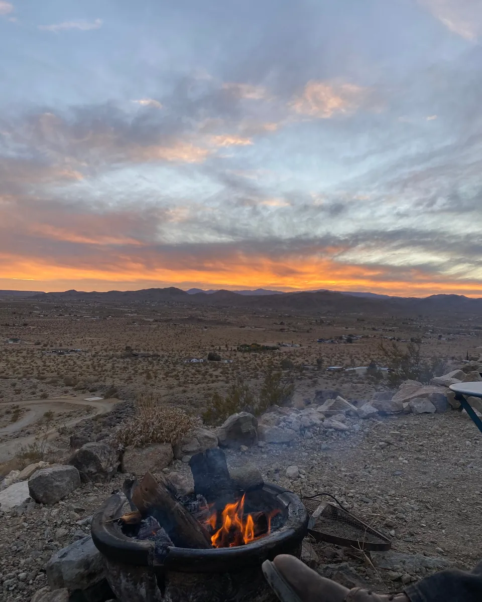 Campfire burning at dusk with the desert sky behind it