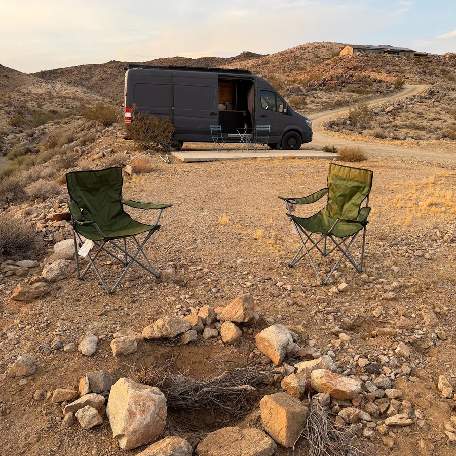 Campsite fire pit ring with chairs and a van